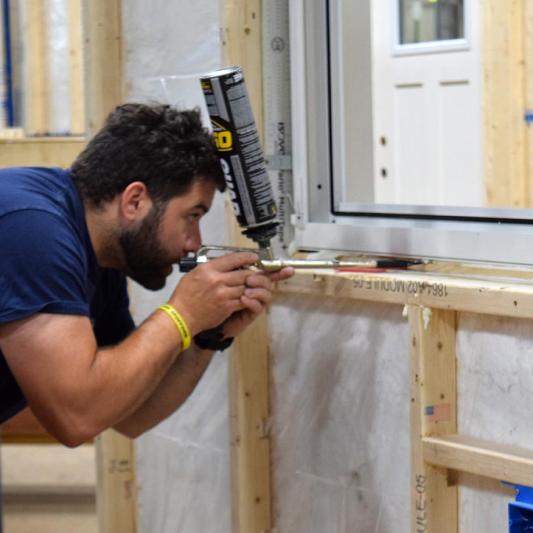 A man applying sealant and membrane to an offsite panel.