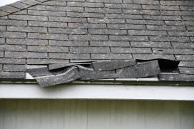 A closeup of a roof with shingles falling off.
